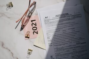 Raport obowiązków KOBiZE z dokumentami leasingu samochodu, kalkulatorem i tabelami emisji na biurku